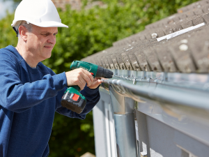 Mill Valley homeowner inspecting gutter corners and joints for leaks, following the gutter care guide.